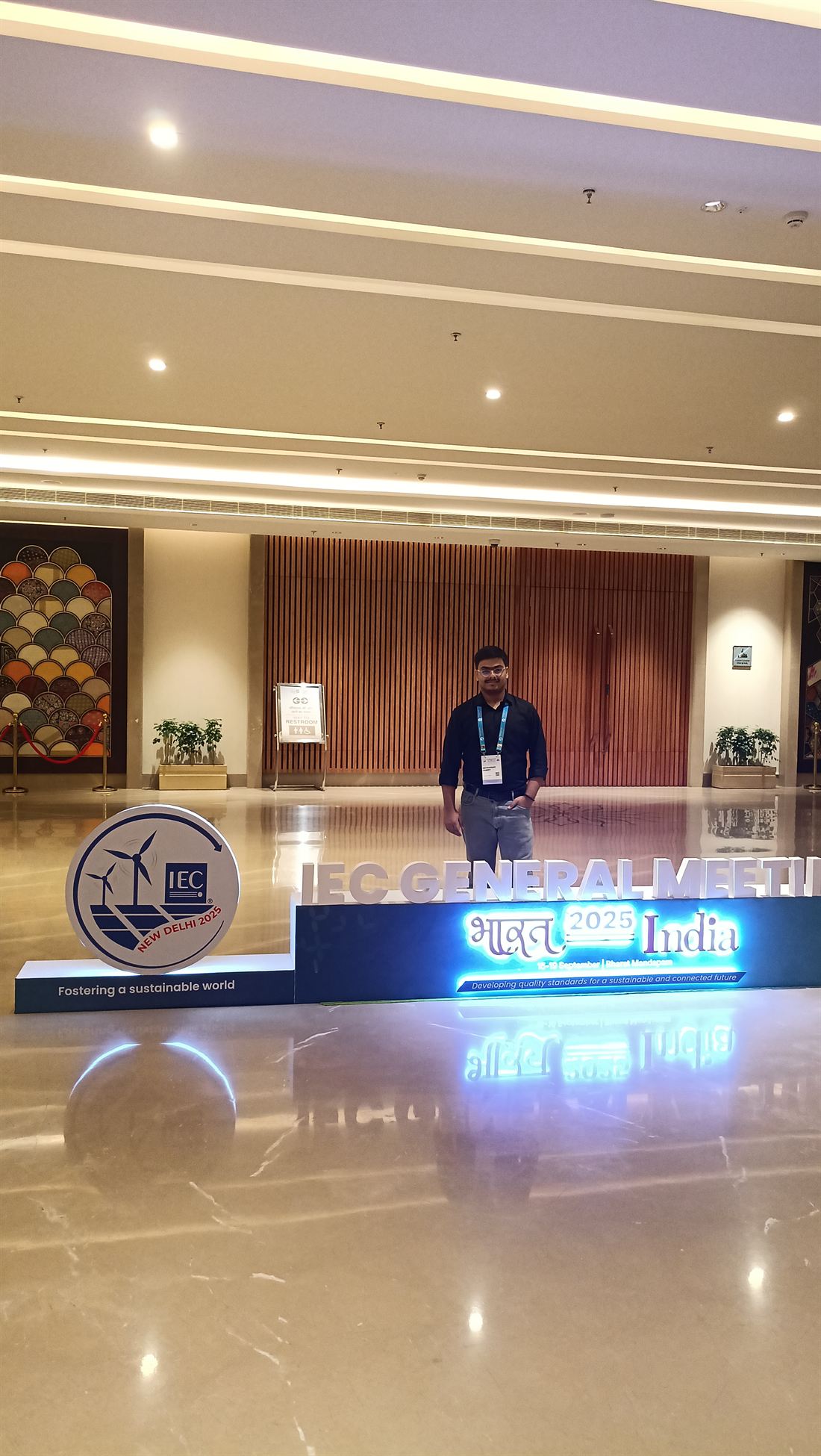 Abhinandan standing behind the IEC General Meeting 2025 sign at Bharat Mandapam, New Delhi