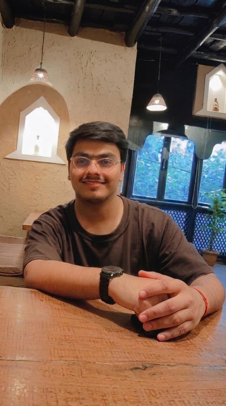 Abhinandan Pandey at a café table in New Delhi, glasses on, smiling at the camera